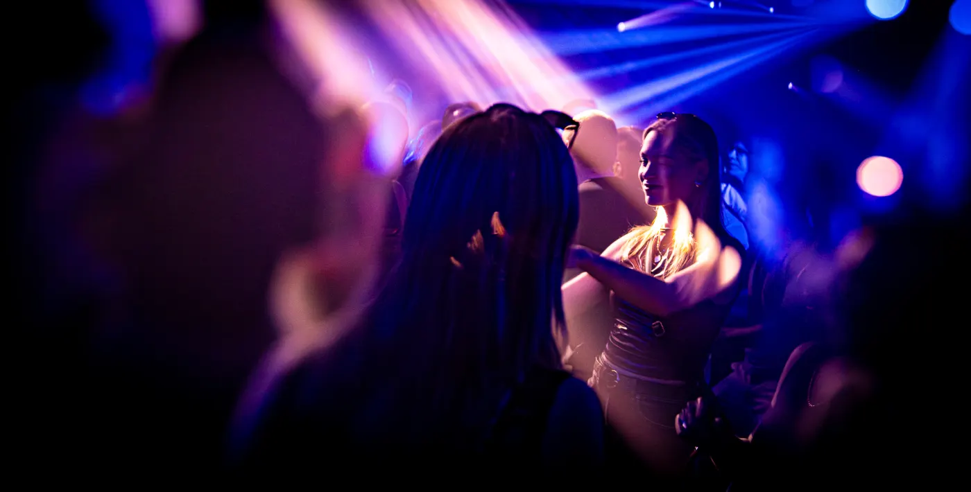 Two people close under purple light