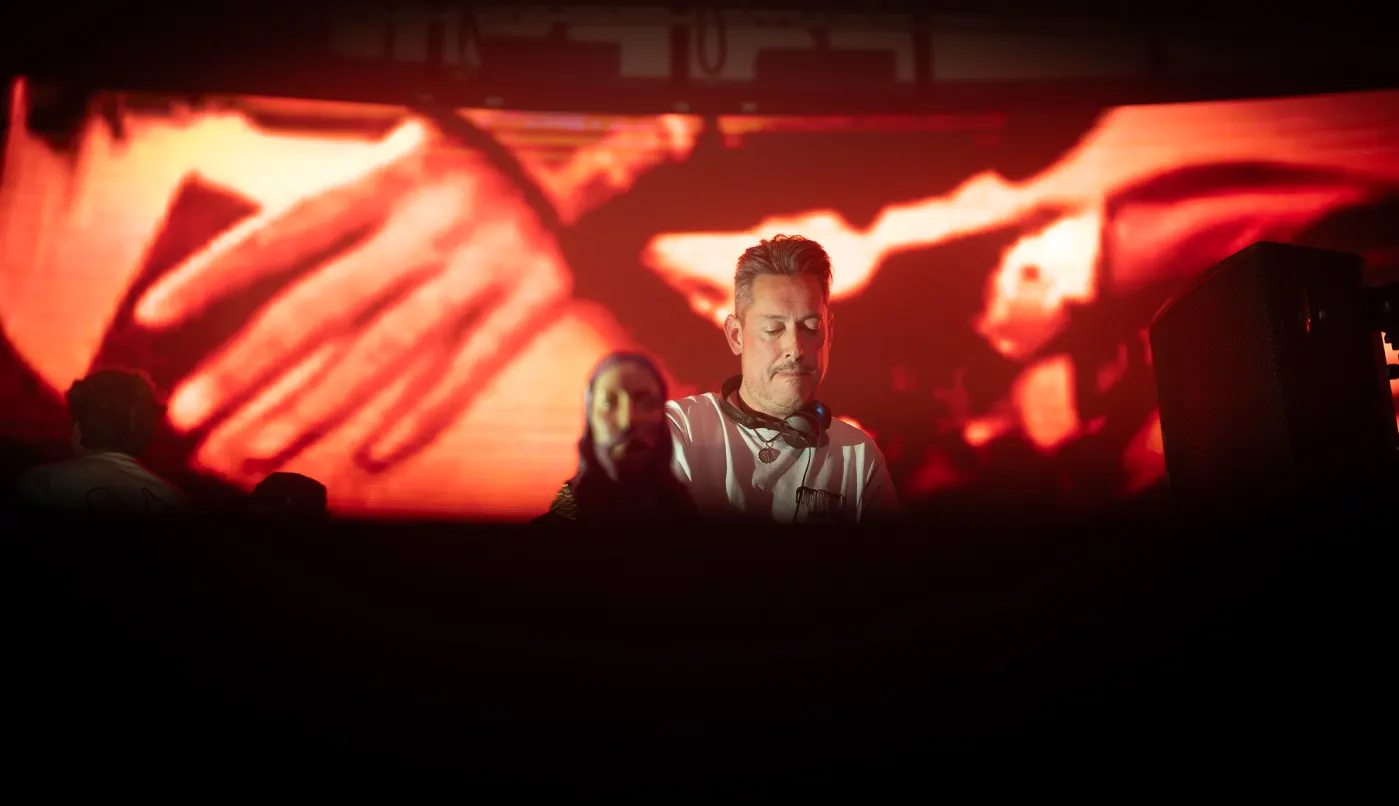 DJ in front of a red screen of hands